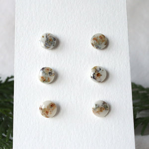 floral wood studs on paper stand, blue resin and wood with greenery in background